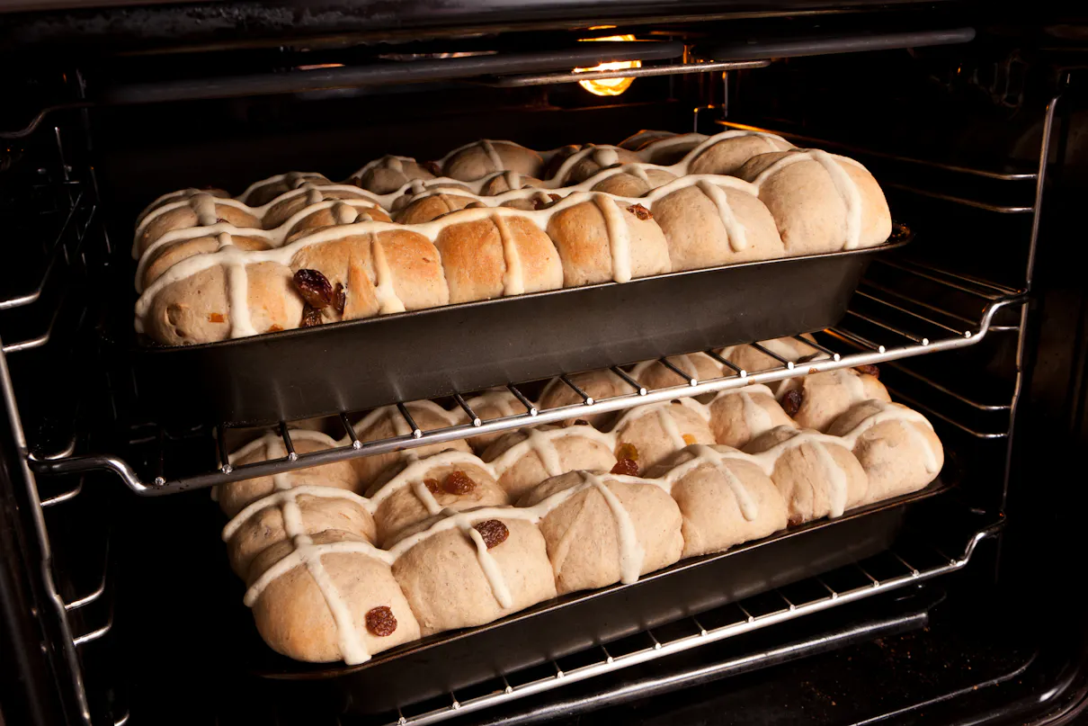 A tray of homemade hot cross buns baking in the oven